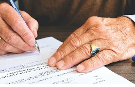 Picture of man's hands signing document.